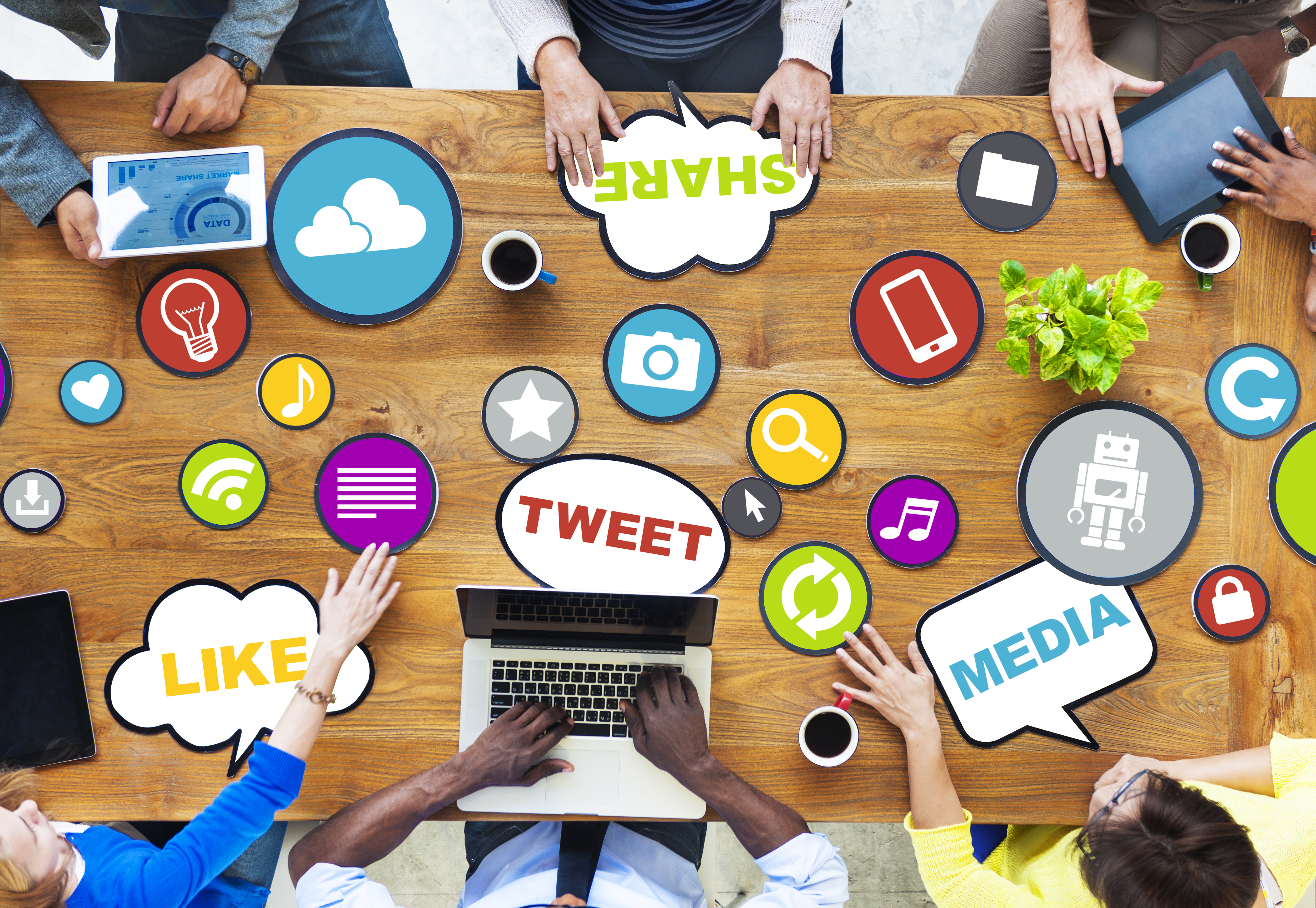 Six persons sitting at desk with multiple social media marketing related logos and words, main points are 'Like','Tweet','Media','Share' and 'Cloud'